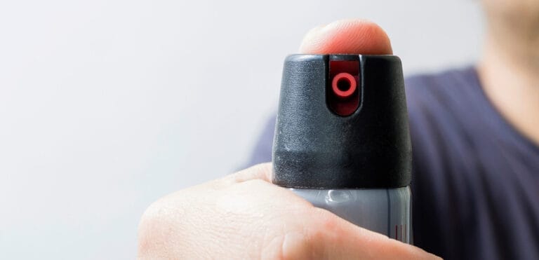 A man holds a canister of tear gas or pepper spray, highlighting self-defense means.