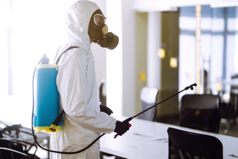 Disinfecting of office to prevent COVID-19, Man in protective hazmat suit with spray chemicals.