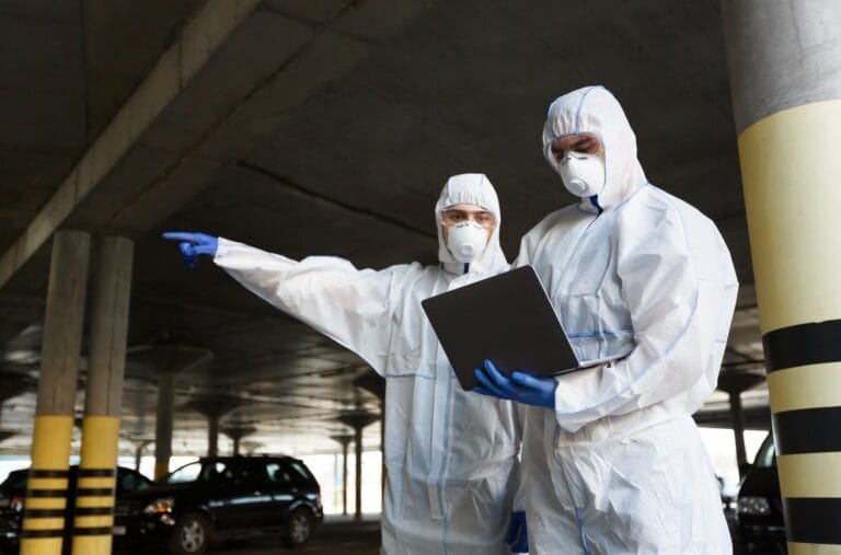 Men in coronavirus hazmats with laptop looking for something