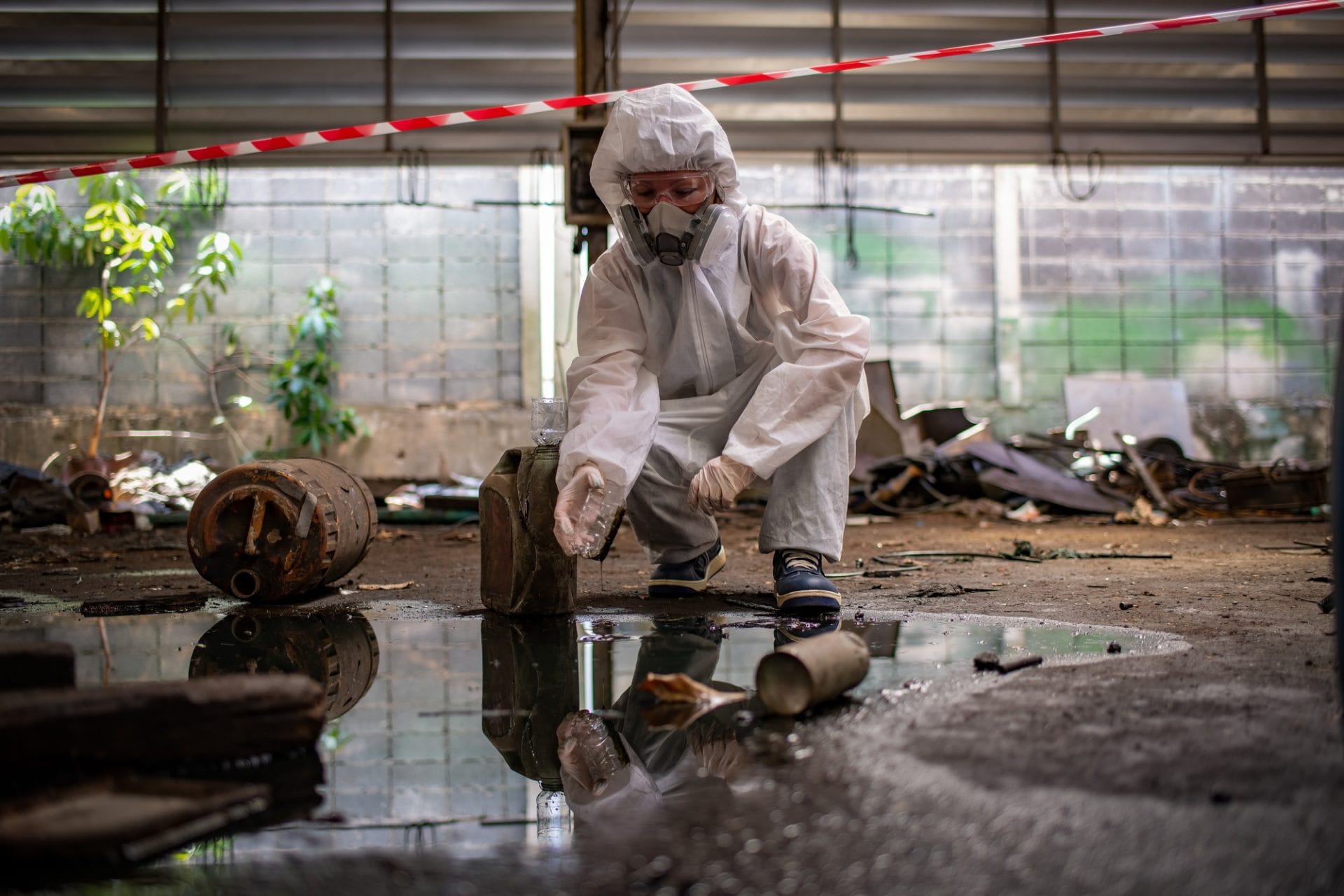 Worker wearing safety uniform and gas mask they used stretching the red white warning tap in spilled
