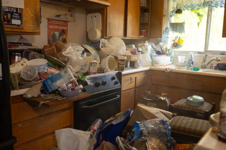 Cluttered room with various household items and debris, illustrating the need for hoarding cleaning services.